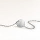 Back of a round silver necklace with a personal engraved date