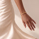 Mannequin en robe en satin crème portant un bracelet jonc personnalisé en or avec une date gravée