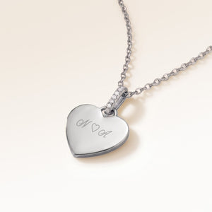 Gros plan de biais du pendentif cœur minimaliste en argent avec zircons blancs et espace pour gravure personnalisée sur le devant et au dos