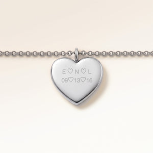 Close-up of minimalist heart-shaped heart pendant in silver with smooth surface and space for personalized engraving on the front and back