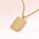 Gros plan d'un pendentif rectangulaire en or à l'effet fondu avec gravure personnalisée d'initiales et d'un cœur au dos poli