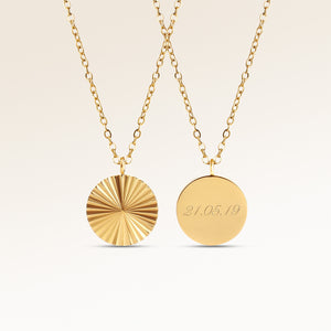 Personalized round gold necklace with ribbed sunburst pattern and space for engraving of text, coordinates or handwriting on the back