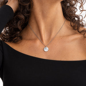 Mannequin en top noir portant un collier rond en argent au motif rayons de soleil striés, avec espace pour une gravure personnalisée de texte, coordonnées ou écriture manuscrite au dos